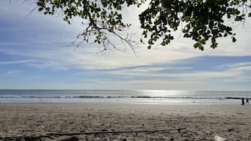 Una playa con cielo despejado, mar tranquilo y restos dispersos.
