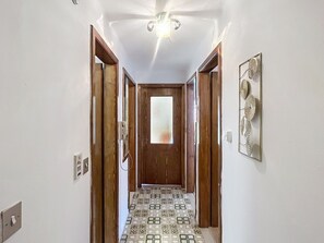 Ein Korridor mit einem gemusterten Boden, Holztüren, einer Deckenleuchte und einem Wanddekor.