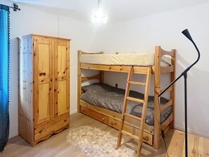 Ein Stockbett mit einer Leiter, einem Kleiderschrank und einer Lampe.