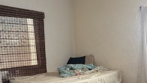 A room with a bed, a window with a metal screen, and a curtain. - HOSTALa (Tala)