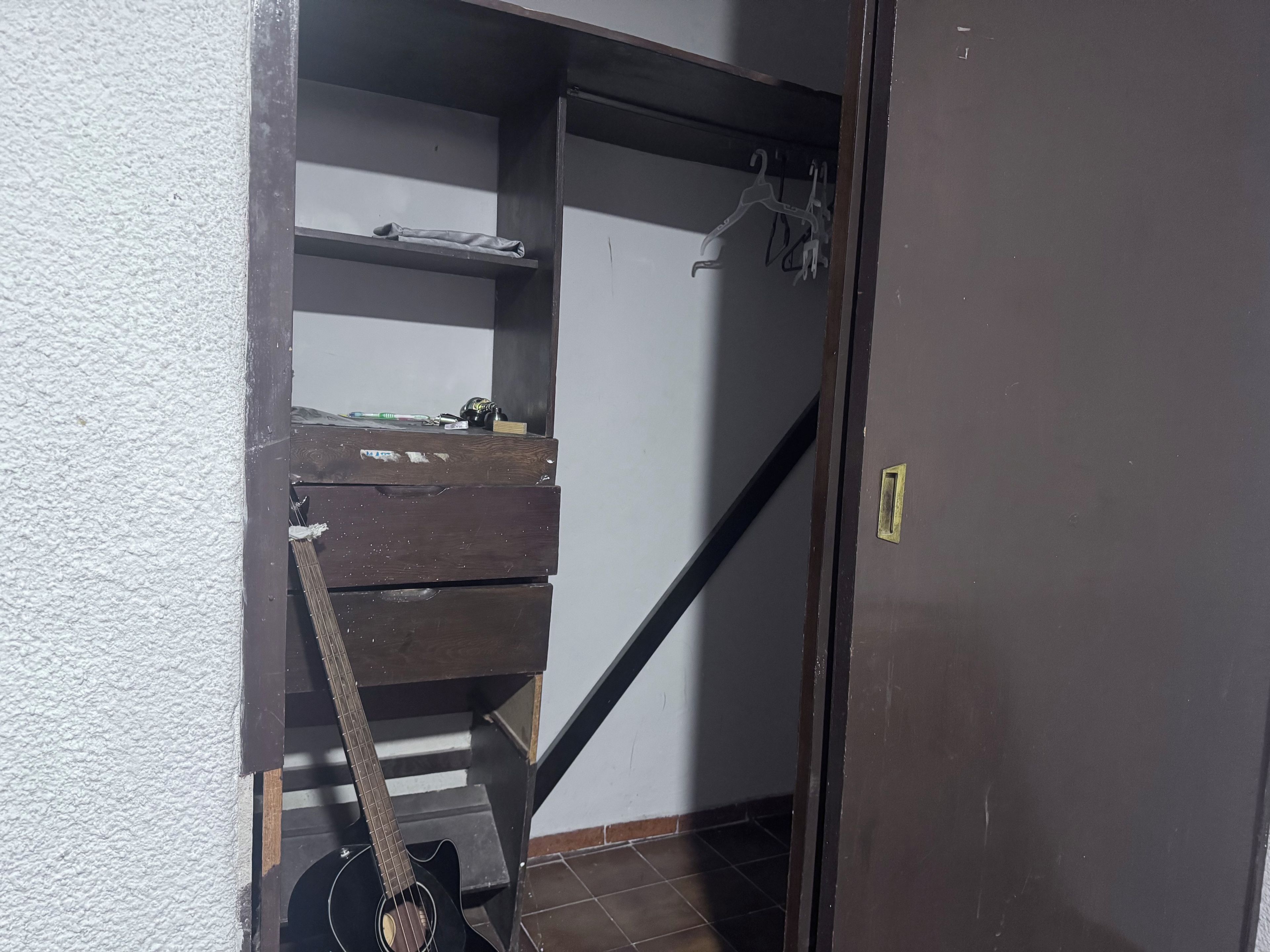 A staircase with a wooden handrail and a guitar leaning against it.