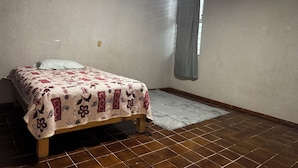 A bedroom with a bed, a window with a curtain, and a tiled floor. - HOSTALa (Tala)