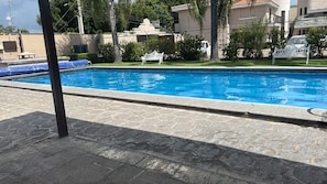 Una piscina amb vora de pedra, envoltada d'una zona verda i una tanca.