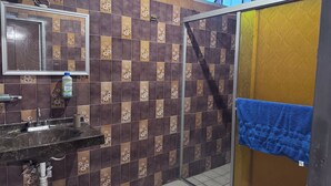A bathroom with a tiled wall, a sink, a mirror, a towel rack, and a shower area. - HOSTALa (Tala)