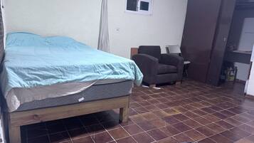 Een kamer met een bed, een stoel, een klein tafeltje en een kast.