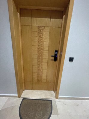 Une porte en bois dotée d’un panneau texturé et d’une serrure électronique moderne.