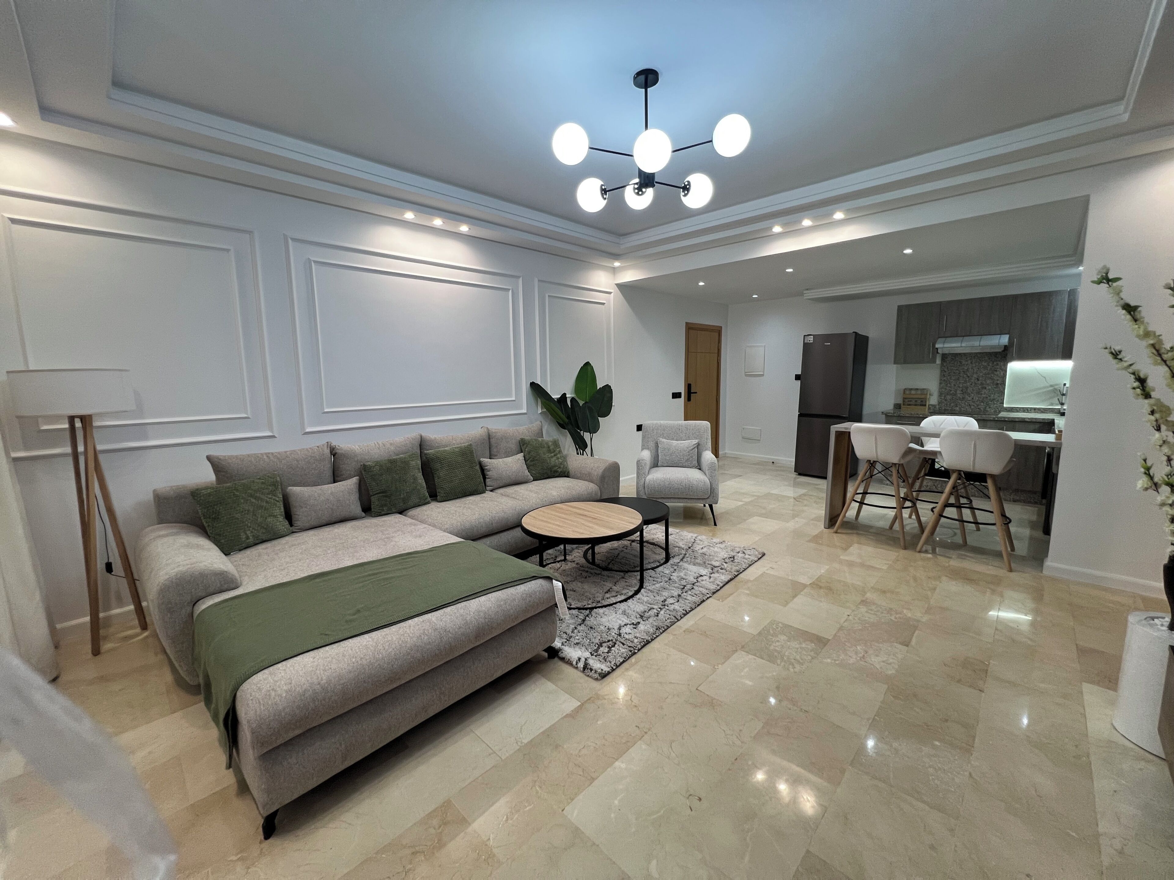 A modern living room with a sectional sofa, a coffee table, and a dining area with chairs.
