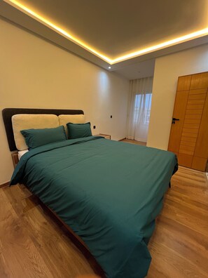 Une chambre à coucher avec un lit, un plancher en bois et une porte.