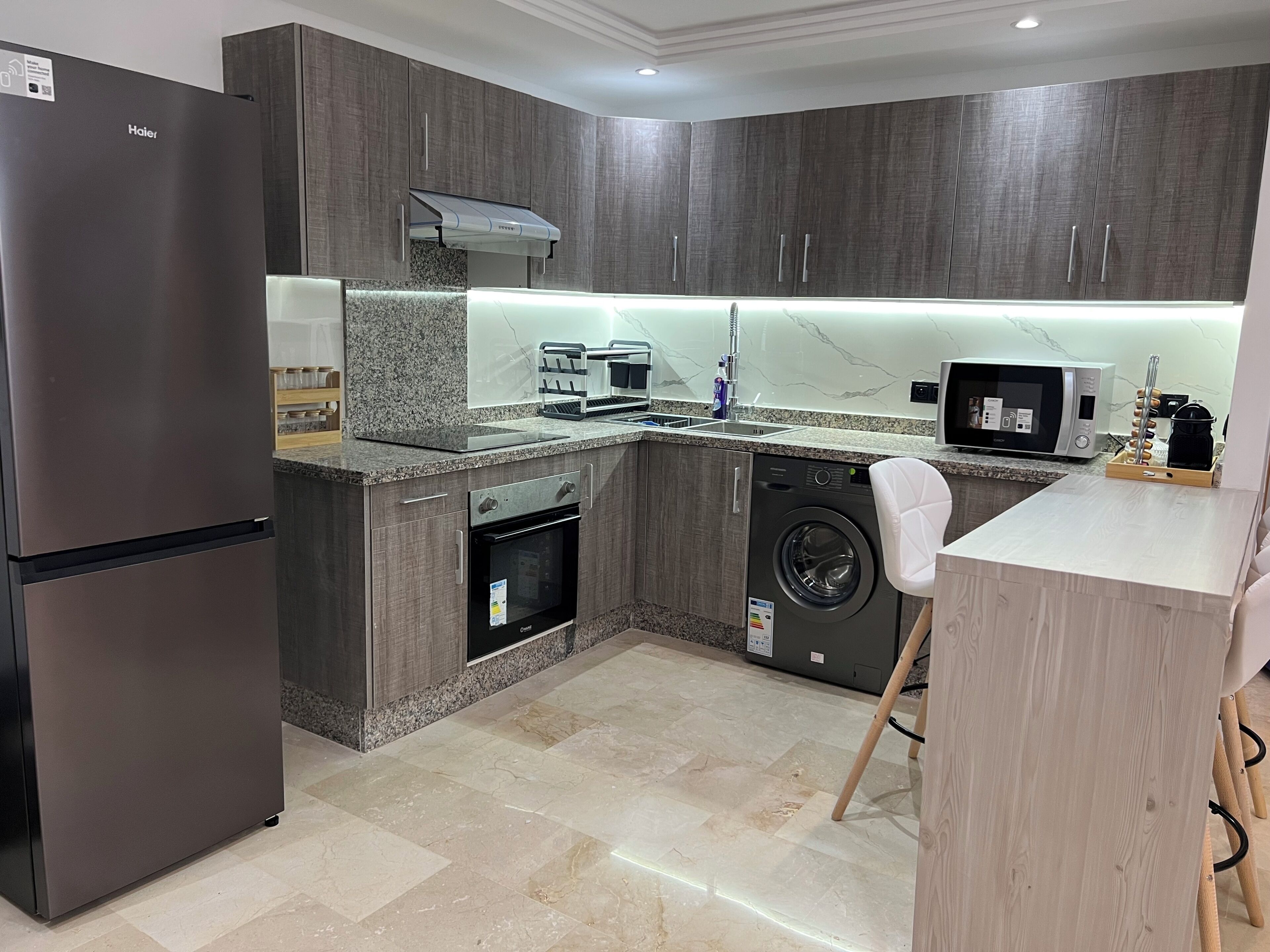 A modern kitchen with a built-in oven, microwave, and washing machine.