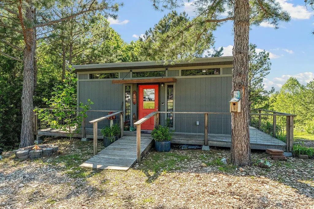 A cabin with a red door, wooden steps, and a small porch.