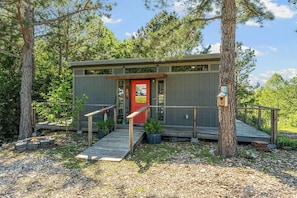 A cabin with a red door, wooden steps, and a small porch. - Pineheaven Couples Cabin (Pineville)