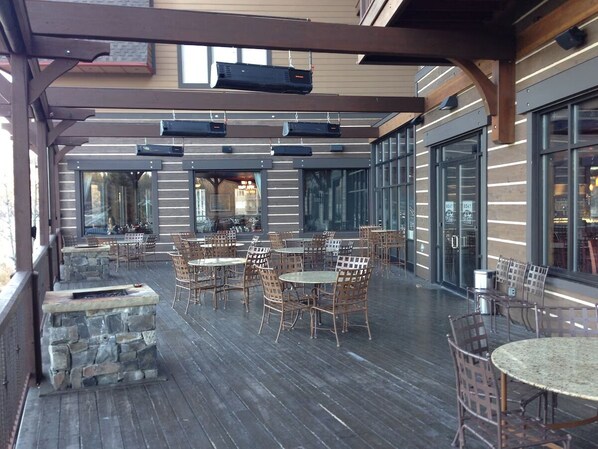 An outdoor patio with stone planters, wooden tables, and wicker chairs.