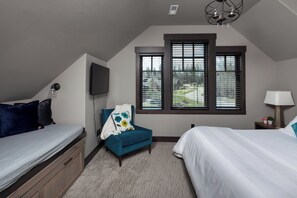 A bedroom with a bunk bed, a single bed, a chair, a TV, and a window with blinds.