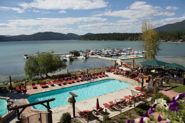 A resort with a swimming pool, lounge chairs, and a dock area. - Hot Tub, Fireplace, Spacious Deck & Serene Views (Whitefish)