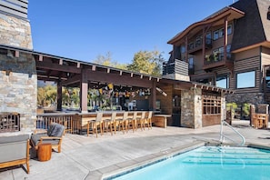 Un espace piscine extérieur avec un bar et des sièges.