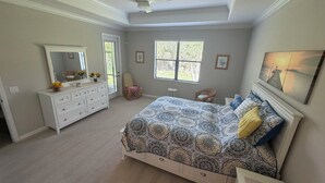 Une chambre à coucher avec un lit, une commode, une chaise et un ventilateur de plafond.