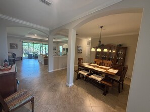 A spacious dining area with a large wooden table, chairs, and a cabinet with dishes. - Naples Retreat with FREE Level 2 EV Charging + Resort Amenities (Naples)