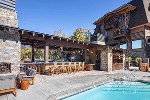Un espace piscine extérieur avec un bar et des sièges.