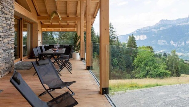 A wooden deck with outdoor furniture, overlooking a mountainous landscape. - Chalet Eteila with Sauna, Jacuzzi and Cinema (Combloux)