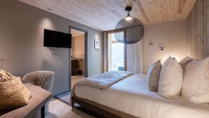 A bedroom with a bed, a television, a sofa, and a window. - Chalet Eteila with Sauna, Jacuzzi and Cinema (Combloux)