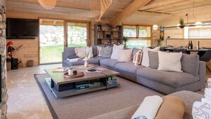 A modern living room with a sectional sofa, a coffee table, and a TV. - Chalet Eteila with Sauna, Jacuzzi and Cinema (Combloux)