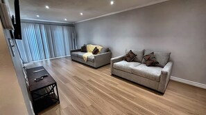 Ein modernes Wohnzimmer mit zwei Sofas, einem Couchtisch und einem an der Wand befestigten Fernseher.