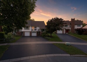 Eine Wohnstraße mit zwei Häusern, jedes mit Garage, Auffahrt und Vorgarten.