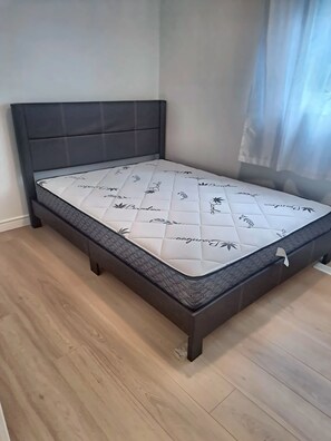 A bed with a headboard and footboard, a mattress with a floral pattern, and a wooden floor.