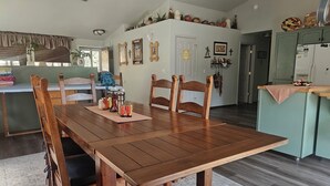 Un comedor con una mesa y sillas de madera, una cocina al fondo y un ventilador de techo.