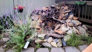 Un jardín con un hogar de piedra rodeado de rocas y plantas.