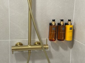 A bathroom with a gold-colored shower system and three bottles of toiletries. - La Casona de les Arts 2 - Oceanográfic (València)