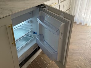 An open refrigerator with multiple shelves and a freezer compartment. - La Casona de les Arts 2 - Oceanográfic (València)