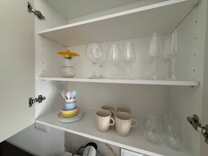 Eine Küchenschrank mit Regalen, auf denen Weingläser, Schüsseln und Tassen stehen.