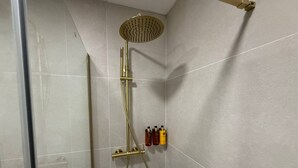 Eine Dusche mit einer goldfarbenen Duschkopf und einem Handbrause-Anschluss.
