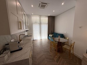 A modern kitchen with a built-in oven, a dining area with a round table and chairs, and a living space with a sofa and curtains. - La Casona de les Arts 2 - Oceanográfic (València)