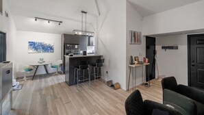 A modern kitchen with a central island, bar stools, and a dining area with a table and chairs.
