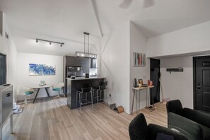 A modern kitchen with a central island, bar stools, and a dining area with a table and chairs.