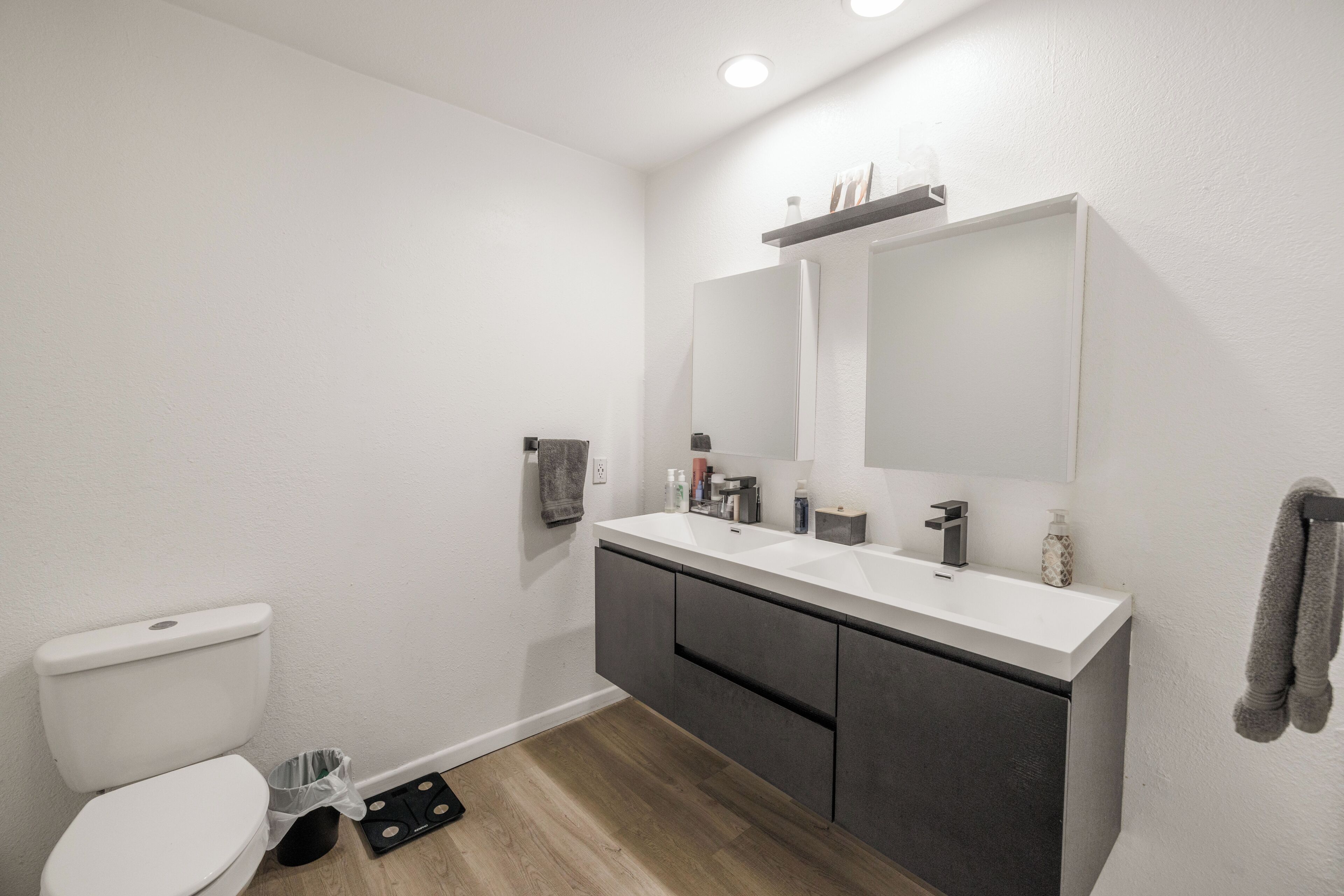 Une salle de bain moderne avec des toilettes blanches, un meuble-lavabo avec un miroir et un évier.