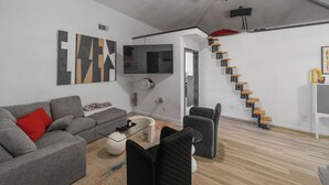 A modern living room with a grey sofa, a coffee table, and a staircase with wooden steps.
