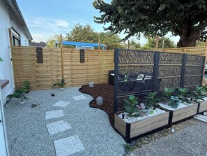 A garden with a wooden fence, decorative panels, and raised flower beds. - Cozy apartment 2 minutes from the ocean (Fouesnant)