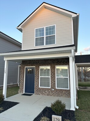 A two-story house with a front porch, a brick facade, and a blue door. - Charming 2 Bed Home near Berea College, I-75  WIFI Provided (Berea)
