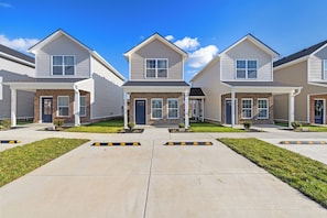 Une rangée de maisons de ville aux façades en briques, dotées de porches et d’allées bien dégagées.