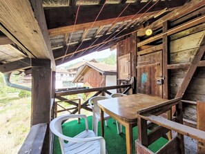 A rustic wooden structure with a table and chairs, a green artificial turf floor, and a view of buildings in the background. - Glanzhirsch Küblis – nahe Klosters/Davos by Interhome (Küblis)
