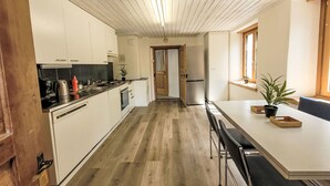 Et moderne køkken med hvide skabe, trægulv og et spiseområde med et bord og stole.