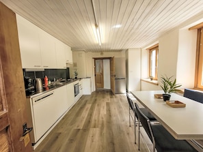 Eine moderne Küche mit weißen Schränken, Holzboden und einem Essbereich mit Tisch und Stühlen.