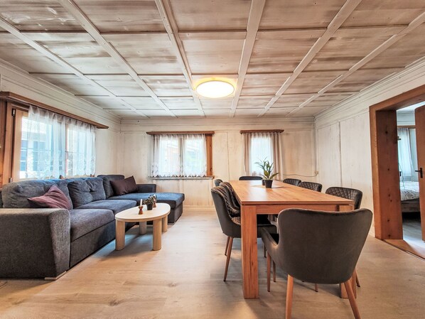 A cozy living room with a sofa, a dining table, and chairs. - Glanzhirsch Küblis – nahe Klosters/Davos by Interhome (Küblis)