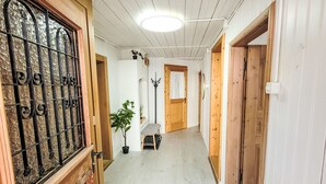 En gang med trædøre, en potteplante og en bænk.