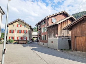A street with traditional buildings, including a two-story house with red shutters and a wooden structure with a no parking sign. - Glanzhirsch Küblis – nahe Klosters/Davos by Interhome (Küblis)