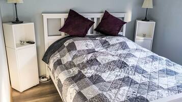 A bedroom with a bed, two nightstands, a lamp on each nightstand, and a wall-mounted picture.