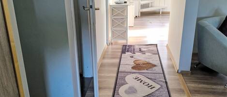 A hallway with a rug featuring a house design and the word 'HOME' on it.